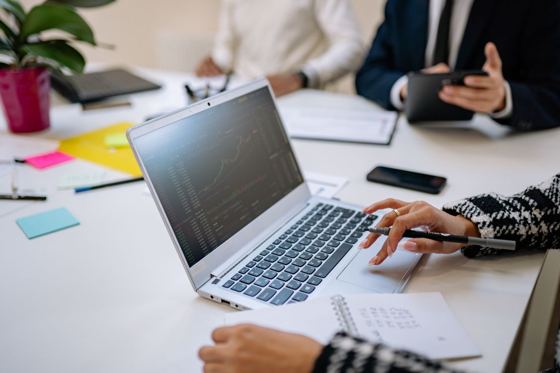 People reviewing a laptop and notes together at a meeting table.